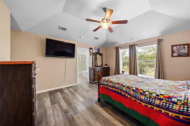 bedroom featuring ceiling fan, ensuite bathroom, vaulted ceiling, and light hardwood / wood-style floors