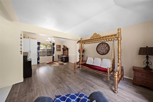 sitting room featuring hardwood / wood-style floors, lofted ceiling, and an inviting chandelier