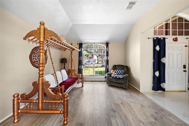 living area featuring a textured ceiling, hardwood / wood-style flooring, and vaulted ceiling