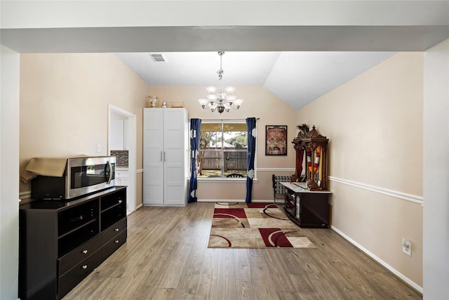 interior space with light wood-type flooring, an inviting chandelier, and vaulted ceiling