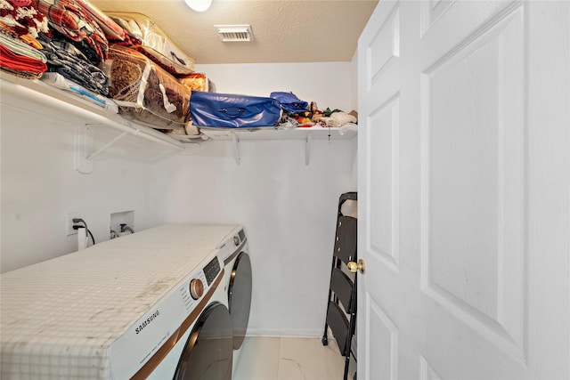 laundry area with independent washer and dryer and a textured ceiling