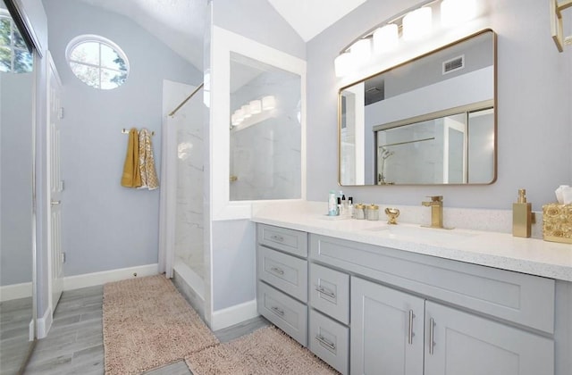 bathroom featuring vanity, vaulted ceiling, and walk in shower