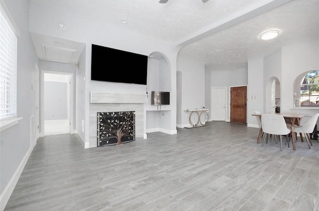 living room with ceiling fan, light wood-type flooring, and a textured ceiling