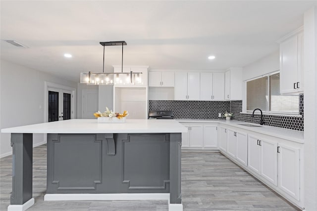 kitchen with white cabinets, a center island, and sink