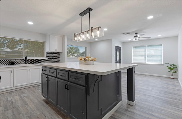 kitchen with pendant lighting, a center island, white cabinets, sink, and decorative backsplash