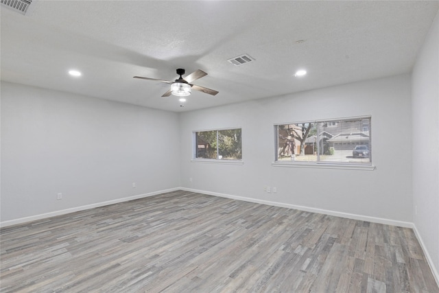 unfurnished room featuring a textured ceiling, light wood-type flooring, and ceiling fan