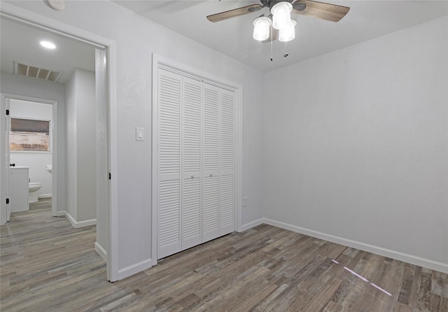 unfurnished bedroom featuring ceiling fan, a closet, and hardwood / wood-style floors