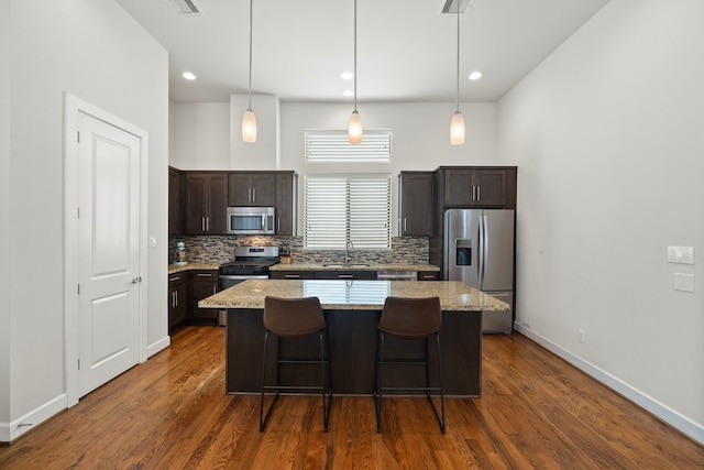 kitchen featuring decorative backsplash, a center island, stainless steel appliances, and light stone counters