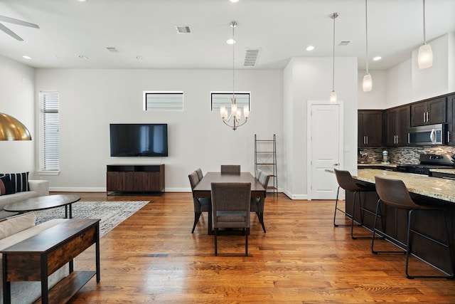 dining area featuring ceiling fan with notable chandelier and light hardwood / wood-style flooring