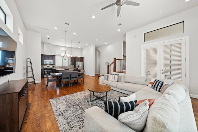 living room with ceiling fan with notable chandelier and dark hardwood / wood-style floors