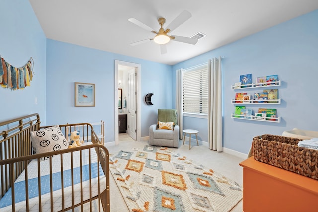 carpeted bedroom featuring ceiling fan, connected bathroom, and a nursery area