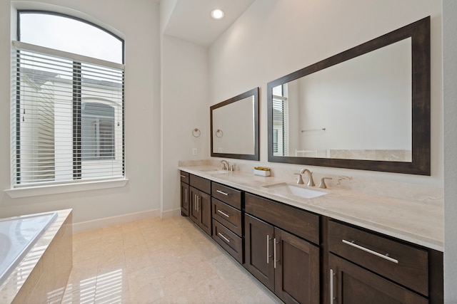 bathroom with tile patterned flooring, vanity, and tiled bath