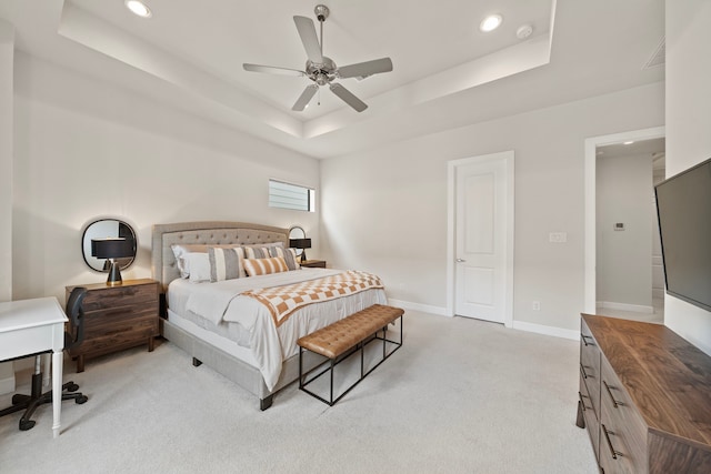 carpeted bedroom with a raised ceiling and ceiling fan