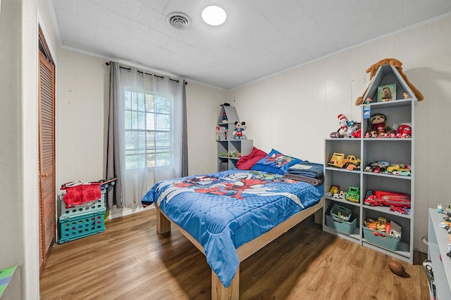 bedroom featuring wood-type flooring, crown molding, and a closet