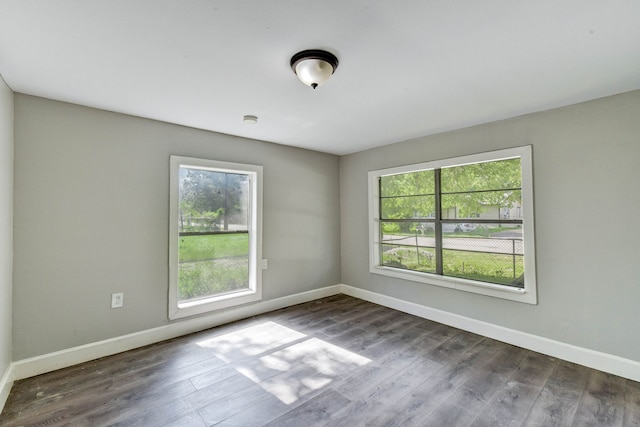 empty room with dark hardwood / wood-style flooring and plenty of natural light