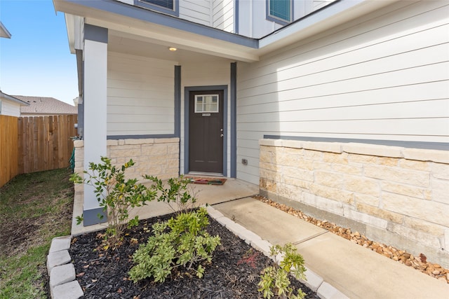 entrance to property with fence and stone siding