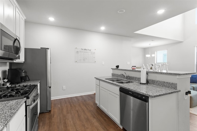 kitchen featuring a center island with sink, a sink, white cabinetry, stainless steel appliances, and dark wood-style flooring