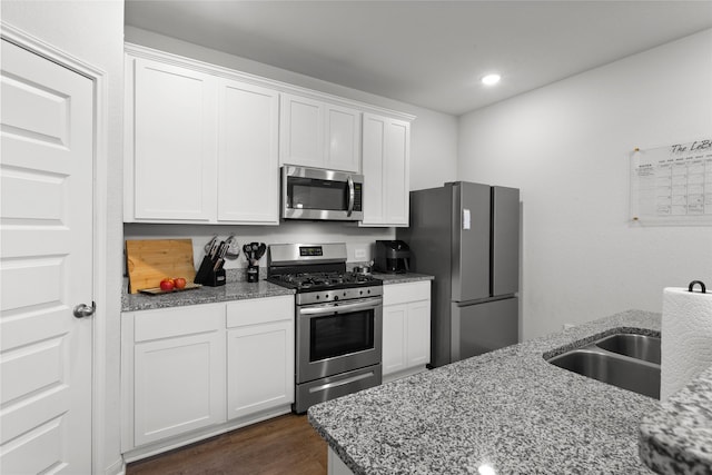 kitchen with white cabinetry, dark wood-style floors, light stone countertops, and stainless steel appliances