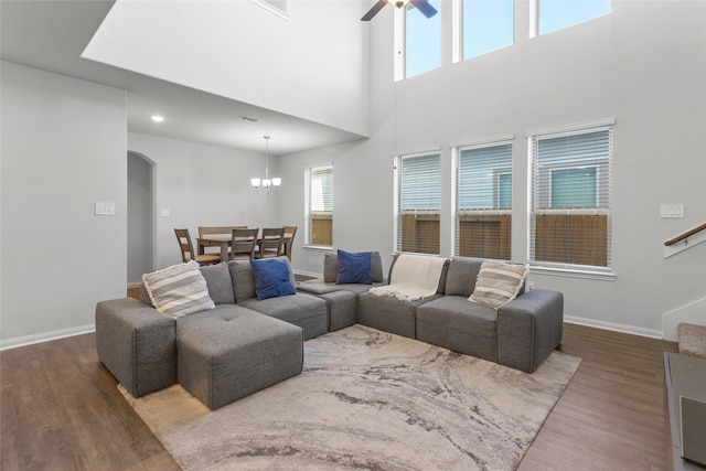 living room featuring ceiling fan with notable chandelier, a high ceiling, and dark hardwood / wood-style floors