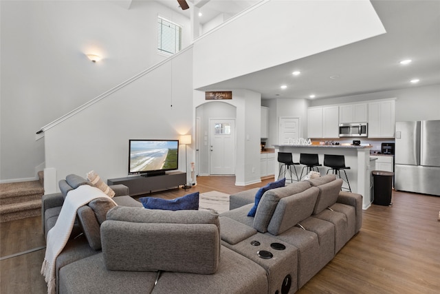 living room with a high ceiling, ceiling fan, and hardwood / wood-style floors