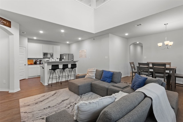 living area with arched walkways, visible vents, recessed lighting, and wood finished floors