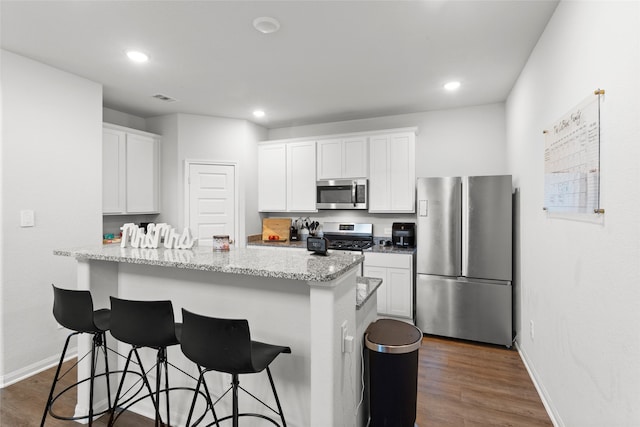 kitchen featuring white cabinetry, a breakfast bar area, dark wood finished floors, and stainless steel appliances