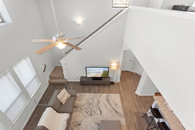 unfurnished living room featuring a fireplace, a towering ceiling, hardwood / wood-style flooring, and ceiling fan