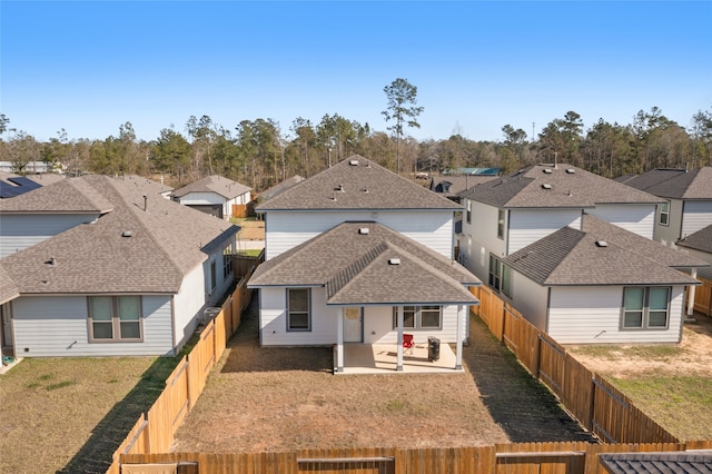 exterior space featuring a patio, a fenced backyard, a shingled roof, a lawn, and a residential view