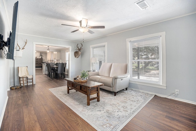 living room featuring ceiling fan, wood-type flooring, a textured ceiling, and ornamental molding