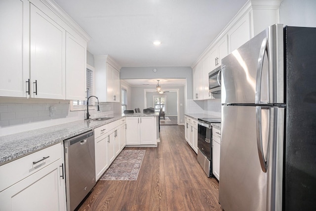 kitchen with white cabinets, sink, appliances with stainless steel finishes, light stone counters, and kitchen peninsula