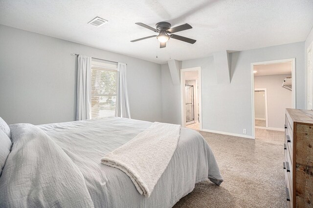 bedroom with connected bathroom, ceiling fan, light carpet, and a textured ceiling