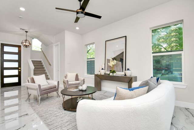 living room with ceiling fan with notable chandelier