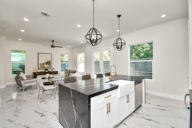 kitchen featuring dishwasher, an island with sink, pendant lighting, white cabinets, and ceiling fan with notable chandelier