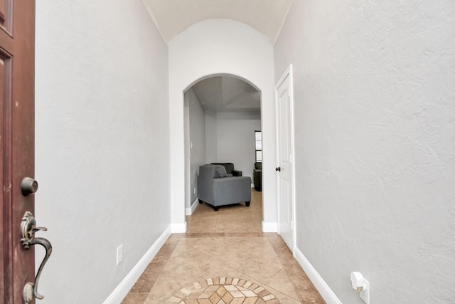 hall featuring lofted ceiling and light tile patterned floors