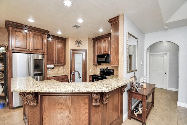 kitchen with kitchen peninsula, decorative backsplash, a kitchen breakfast bar, sink, and black appliances