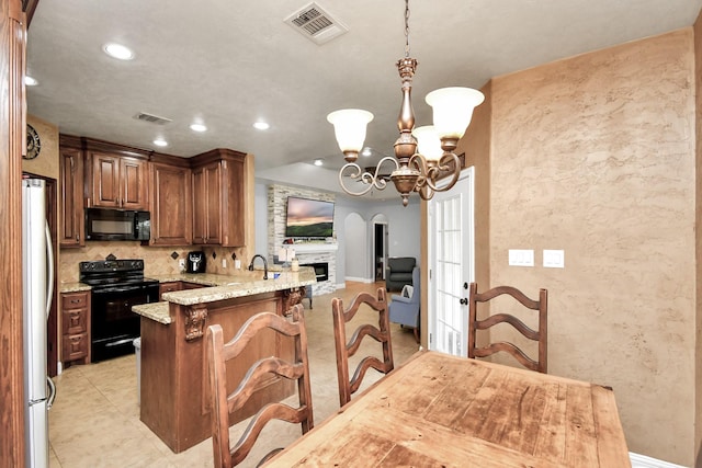 kitchen with black appliances, light stone counters, kitchen peninsula, a breakfast bar area, and a chandelier