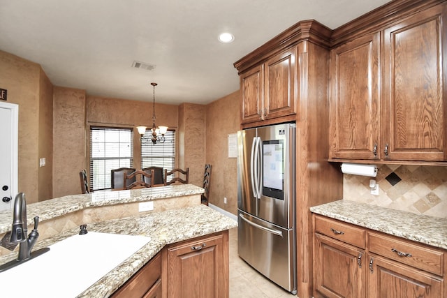 kitchen with backsplash, sink, stainless steel fridge, light tile patterned floors, and a chandelier