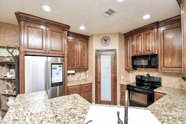 kitchen with black appliances, decorative backsplash, and light stone countertops