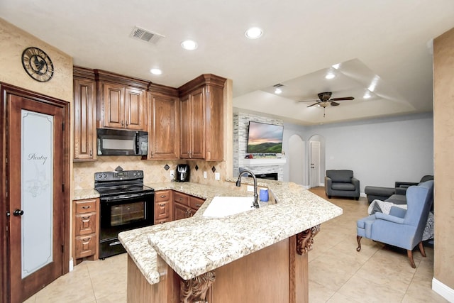 kitchen featuring kitchen peninsula, a tray ceiling, ceiling fan, sink, and black appliances