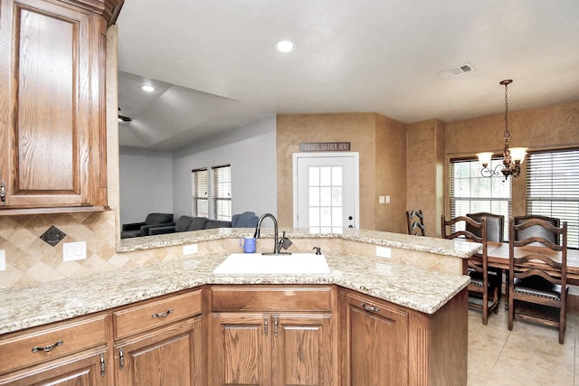 kitchen featuring decorative backsplash, kitchen peninsula, sink, and an inviting chandelier