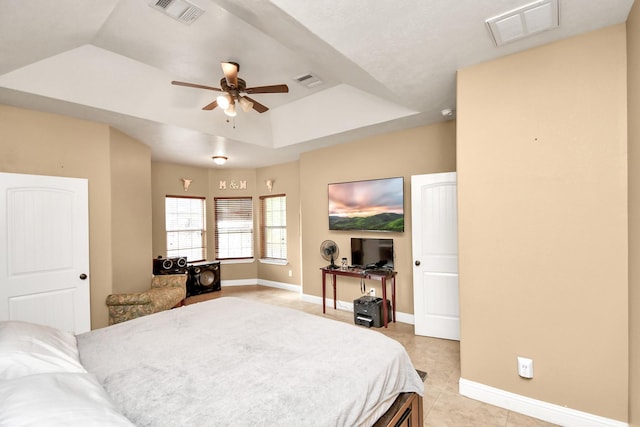 bedroom with ceiling fan, light tile patterned floors, and a tray ceiling