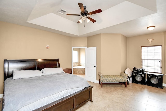 bedroom with ceiling fan, a raised ceiling, and connected bathroom