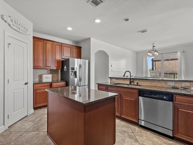 kitchen with sink, appliances with stainless steel finishes, a center island, tasteful backsplash, and a notable chandelier