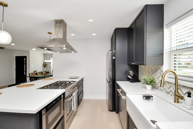 kitchen with island exhaust hood, appliances with stainless steel finishes, backsplash, sink, and pendant lighting