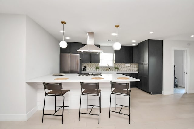 kitchen featuring a kitchen breakfast bar, backsplash, appliances with stainless steel finishes, decorative light fixtures, and range hood