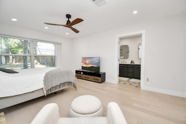 bedroom with ensuite bathroom, light hardwood / wood-style flooring, and ceiling fan