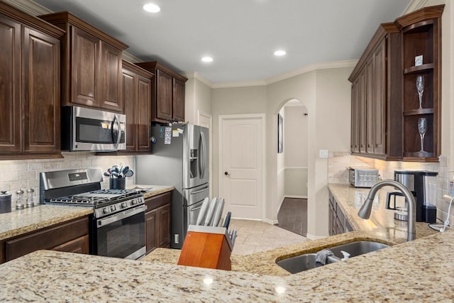 kitchen featuring tasteful backsplash, light stone counters, sink, and stainless steel appliances