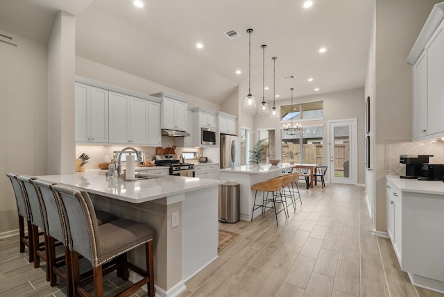 kitchen with white cabinetry, a large island, hanging light fixtures, stainless steel appliances, and a breakfast bar