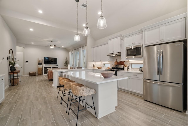 kitchen featuring a center island, hanging light fixtures, ceiling fan, appliances with stainless steel finishes, and white cabinetry