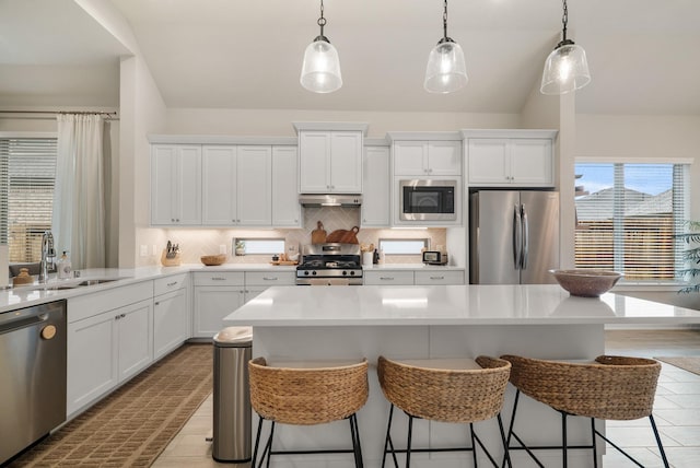 kitchen featuring tasteful backsplash, a kitchen island, decorative light fixtures, and appliances with stainless steel finishes